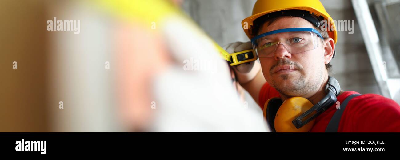 Builder measuring wall level with roulette tape Stock Photo