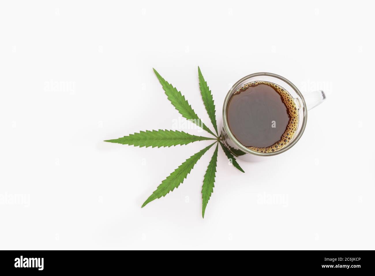 Cup of cannabis-infused coffee with marijuana leaf on white background. Top view with space for text Stock Photo