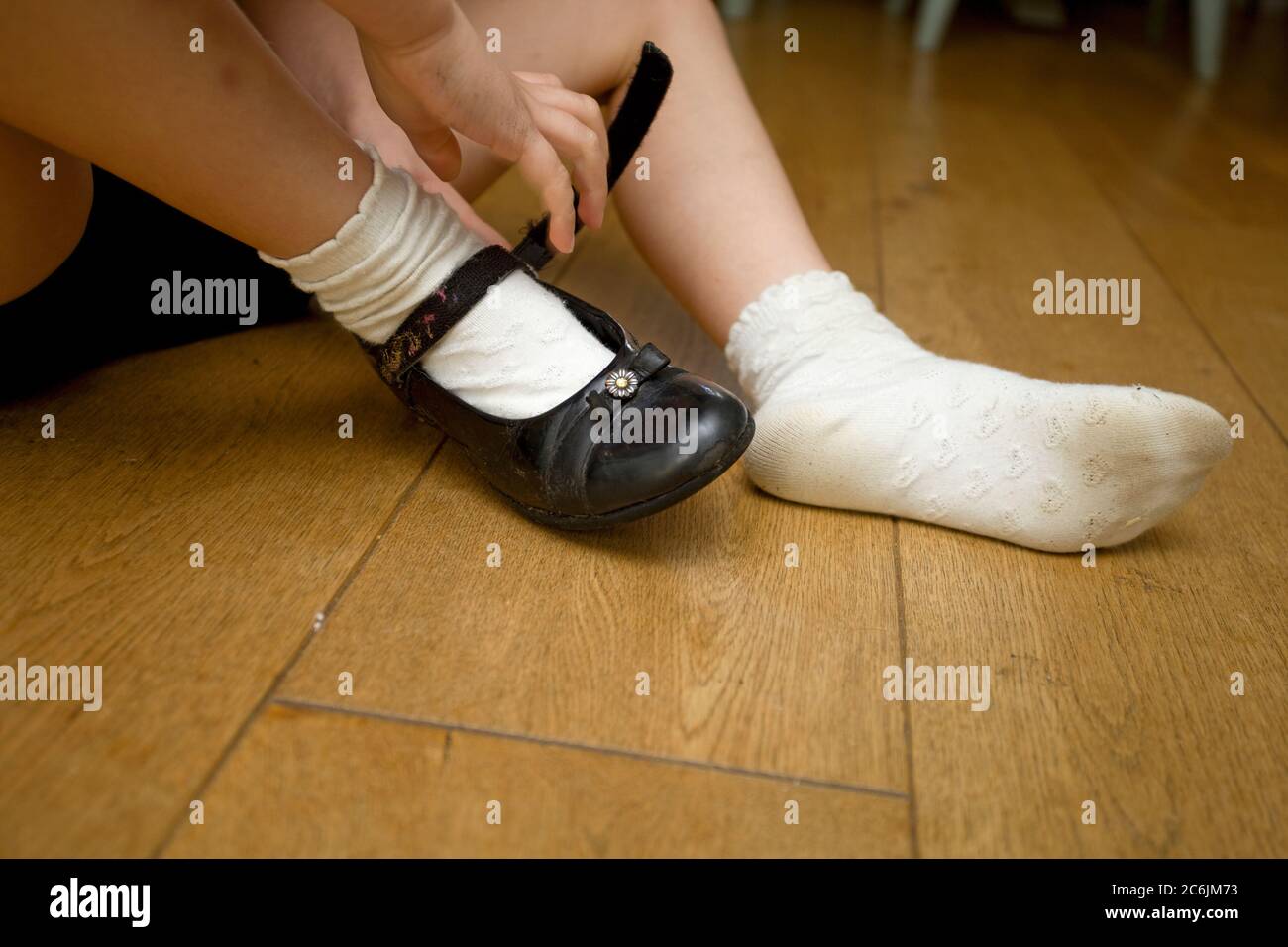 Young girl taking school shoes off Stock Photo