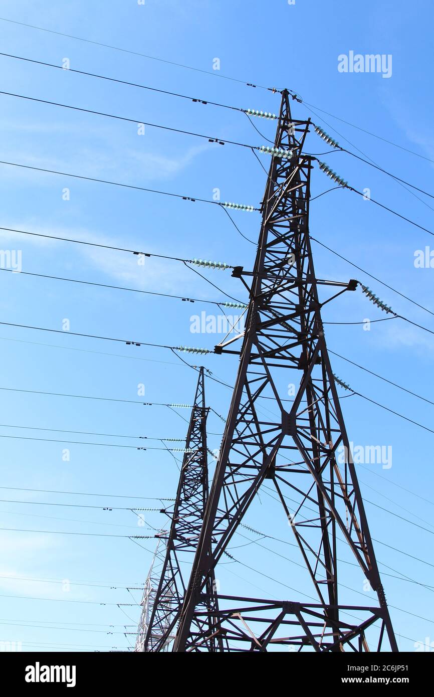 Electric high voltage tower against the blue sky. Wires on a metal ...