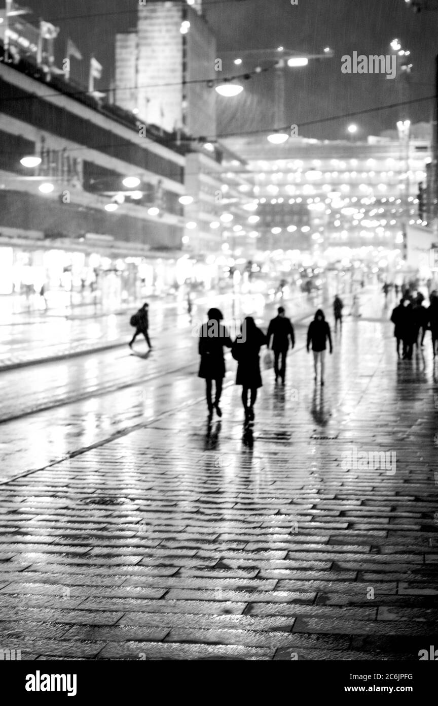 Silhouettes of people walking in rain in city street. Stock Photo