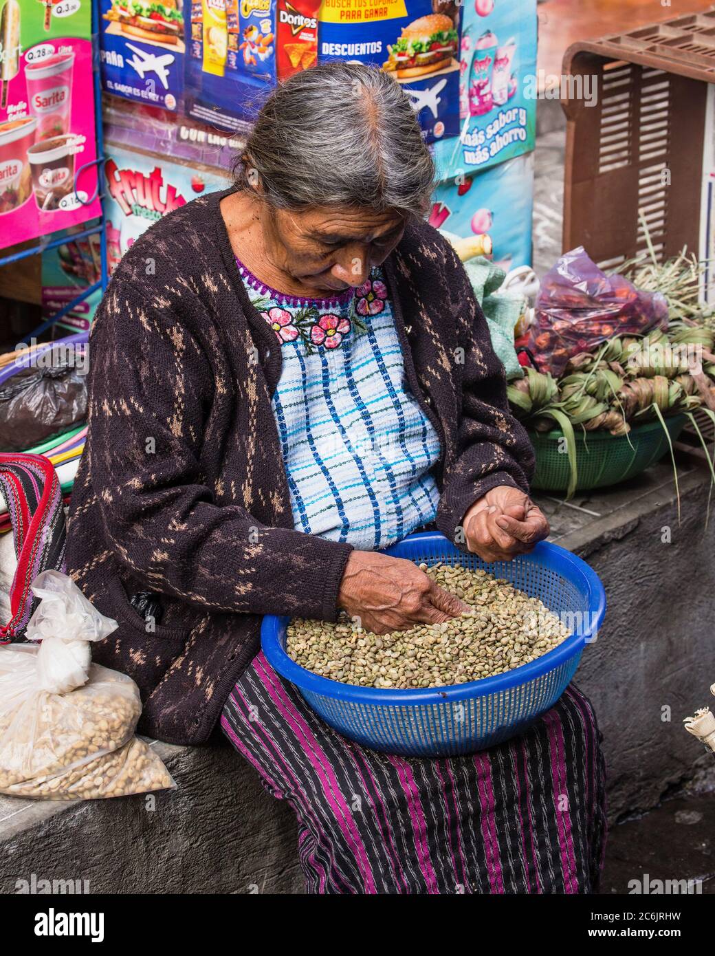 Guatemala, Solola Department, Santiago Atitlan, A Mayan woman wearing traditional dress sorts nuts for sale in the market. Stock Photo