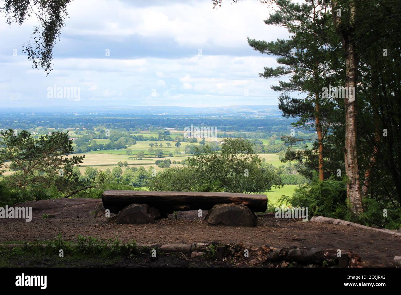 View of Cheshire from the stormy point area, inc a wooden bench and trees, at Alderley edge in Cheshire, England Stock Photo