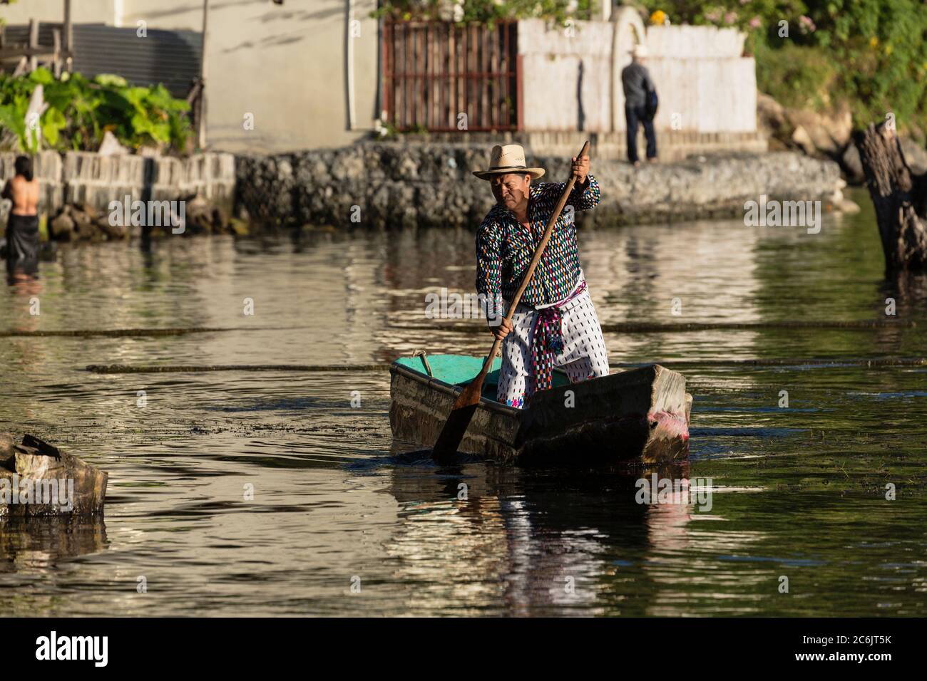 Guatemala, Solola Department, San Pedro la Laguna, A Tzutujil Mayan man in the traditional dress of San Pedro la Laguna paddles his cayuco or fishing canoe on Lake Atitilan. Stock Photo