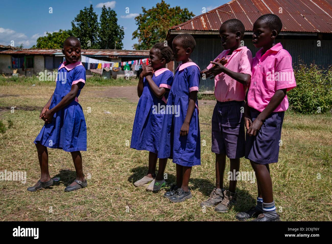 A young schoolgirl takes the lead and encourages her classmates to follow along in a presentation at her school in Ahero, Kenya Stock Photo