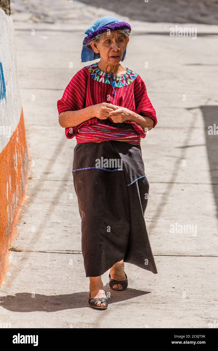 An older Cakchiquel Mayan woman in traditional dress walks down the street in Santa Cruz la Laguna, Guatemala. Stock Photo