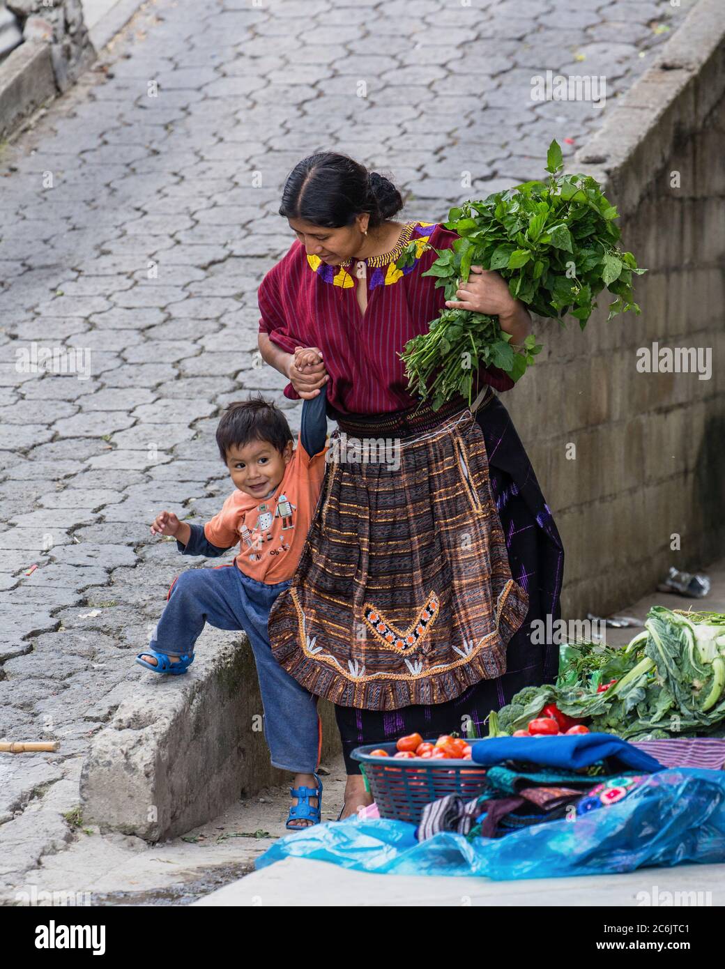 Guatemala, Solola Department, Santa Cruz la Laguna, A Cakchiquel Mayan mother in traditional dress helps her young son. Stock Photo