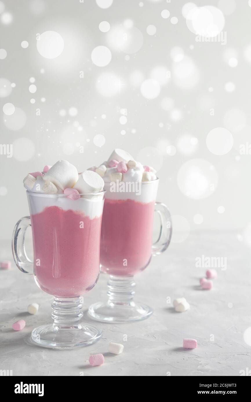 Pink ruby hot chocolate with whipped cream and marshmallow candy in a 2 glass mugs. Christmas mood. Copy space, Vertical. Stock Photo