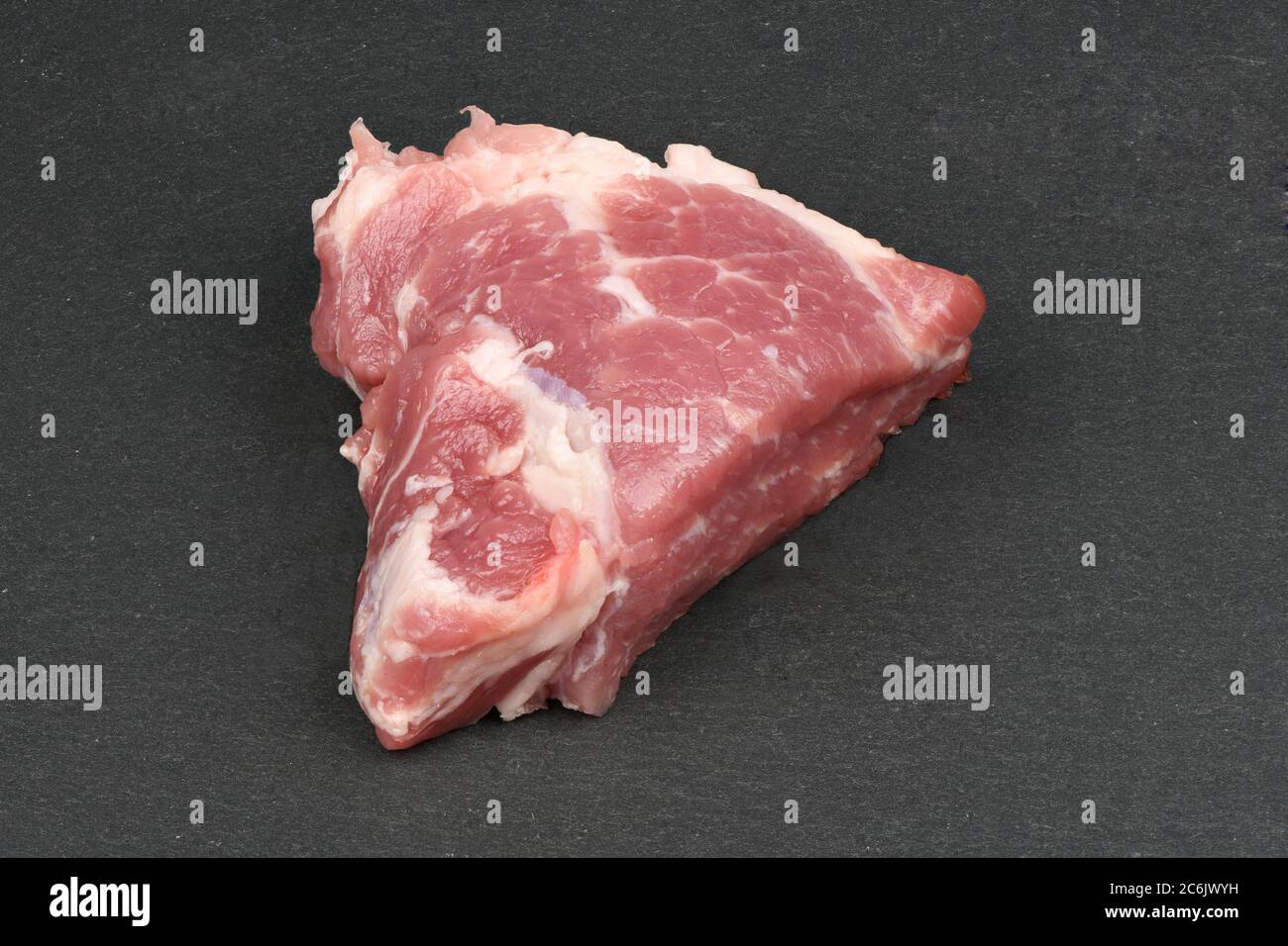 Fresh raw pork steak isolated on black slang stone. High resolution