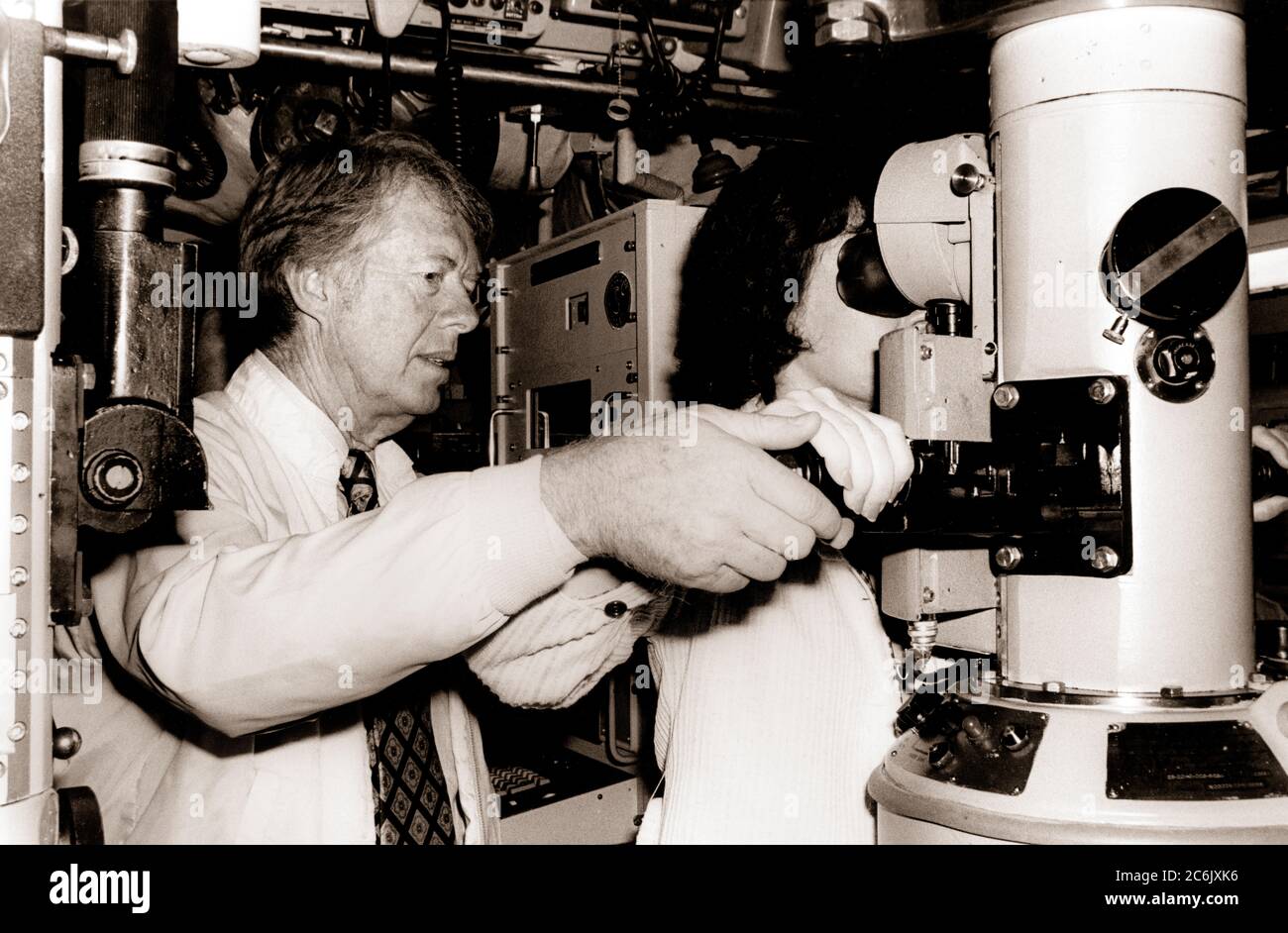 CAPE CANAVERAL, Fla. (May 27, 1977) President Jimmy Carter assists first lady Rosalynn Carter as she looks through the periscope of the nuclear powered submarine USS Los Angeles (SSN 688) during a cruise.James Earl (Jimmy) Carter, Jr., who in 1976 became the fifth consecutive President with prior Navy service, from Plains, Georgia born to Lillian Gordy and James Earle Carter. Carter grew up in a rural atmosphere and attended public schools. Graduating from Plains High School in 1941, he attended Georgia Southwestern College in Americus, Georgia. After a year there, Carter transferred to Georgi Stock Photo