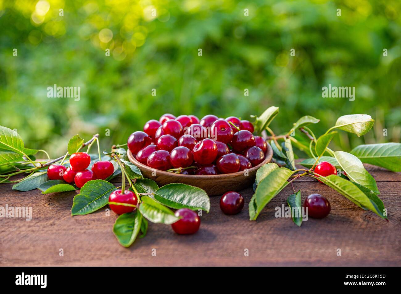 Cherries in a wooden bowl on a wooden table, outdoor shot Stock Photo