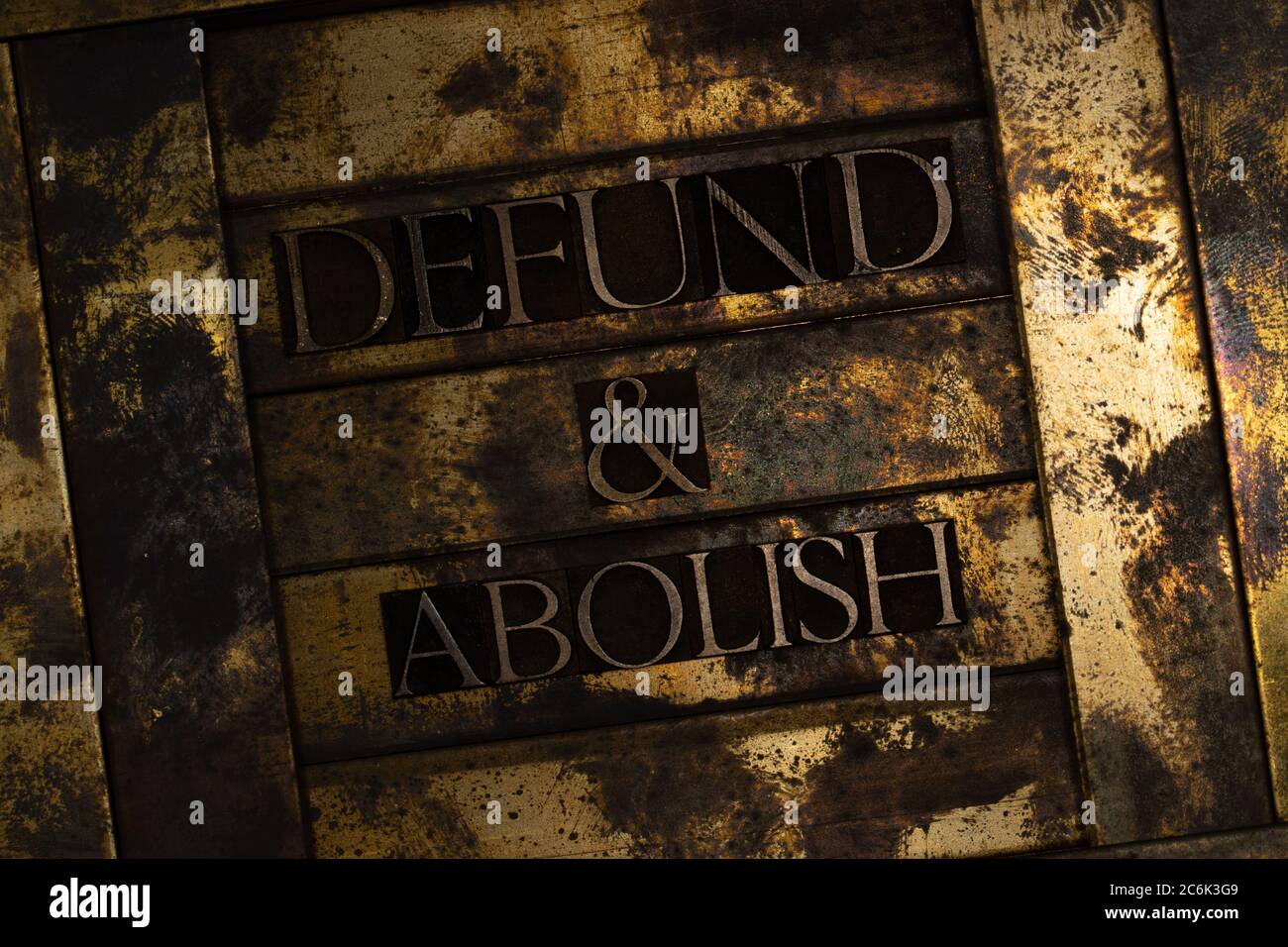 Defund and Abolish text formed with real authentic typeset letters on vintage textured silver grunge copper and gold background Stock Photo