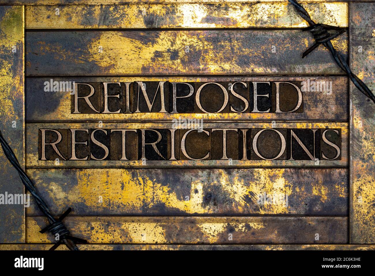 Reimposed Restrictions text formed with real authentic typeset letters on vintage textured silver grunge copper and gold background Stock Photo