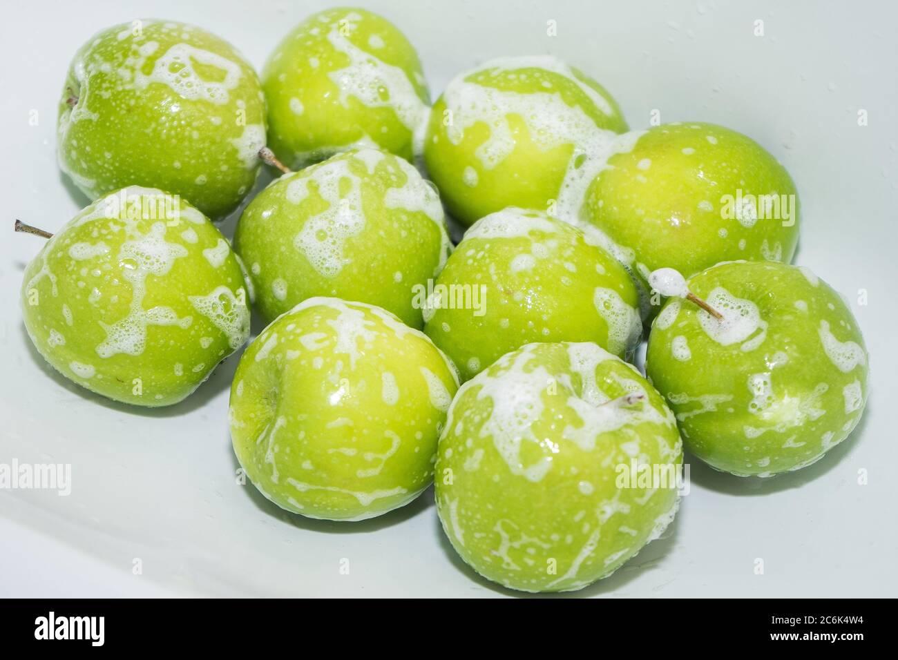 Washing fruit. Soapy green apples in the sink.  Stock Photo