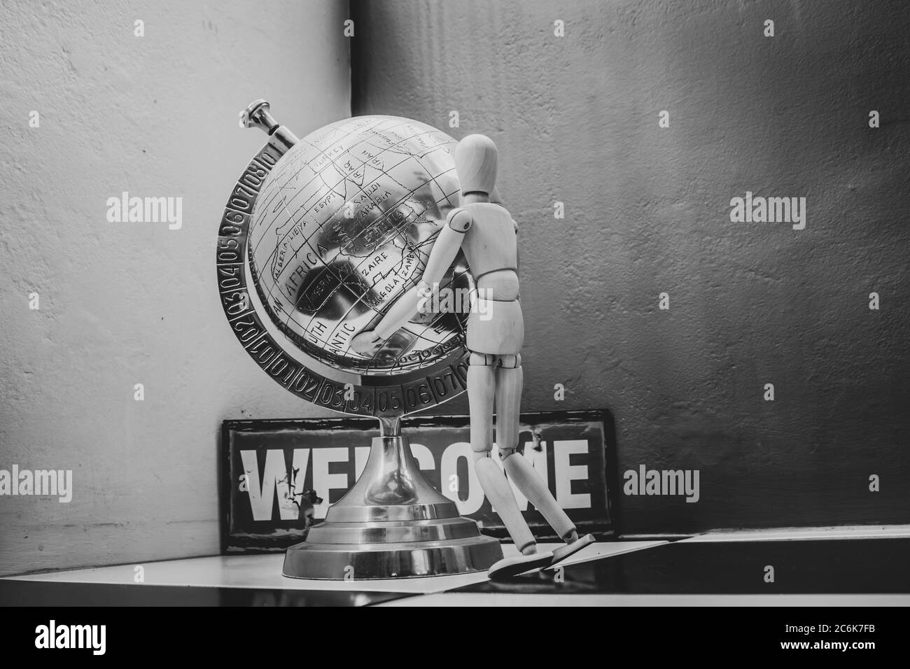 Wooden Human Manikin posing with an ornamental silver world globe Stock