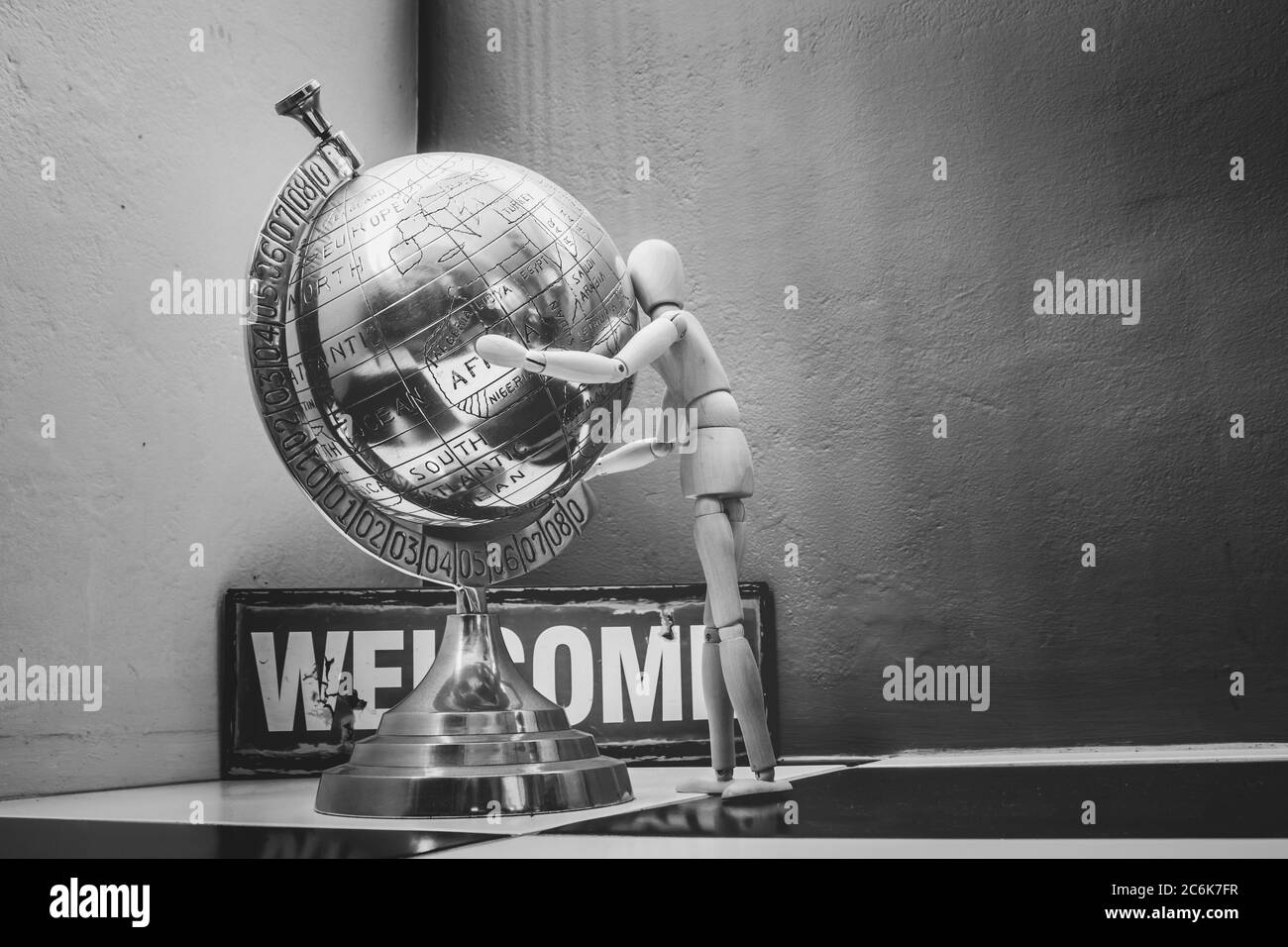 Wooden Human Manikin posing with an ornamental silver world globe Stock