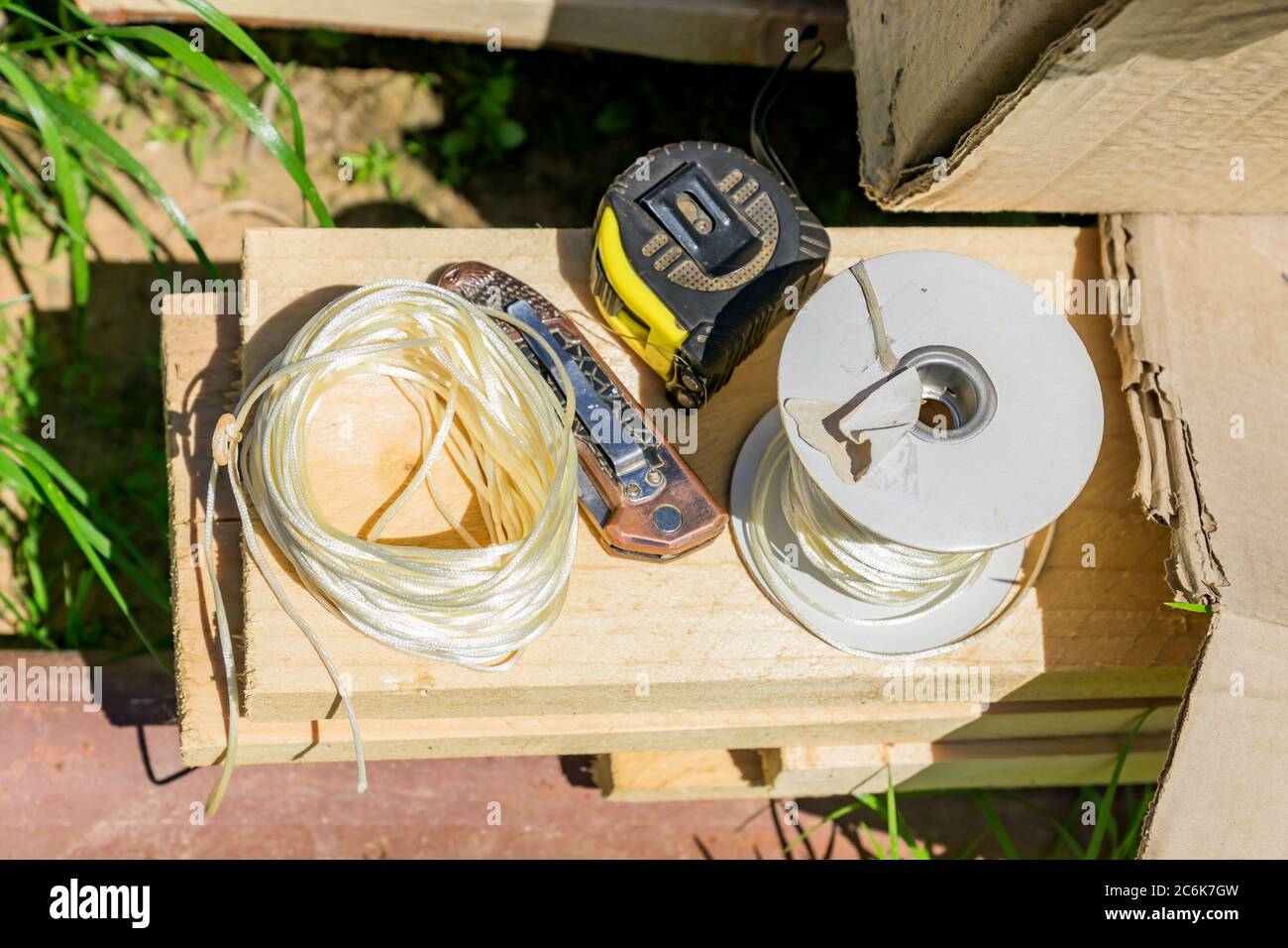 working tools tapemeasure, twine and pocket knife on wooden desk