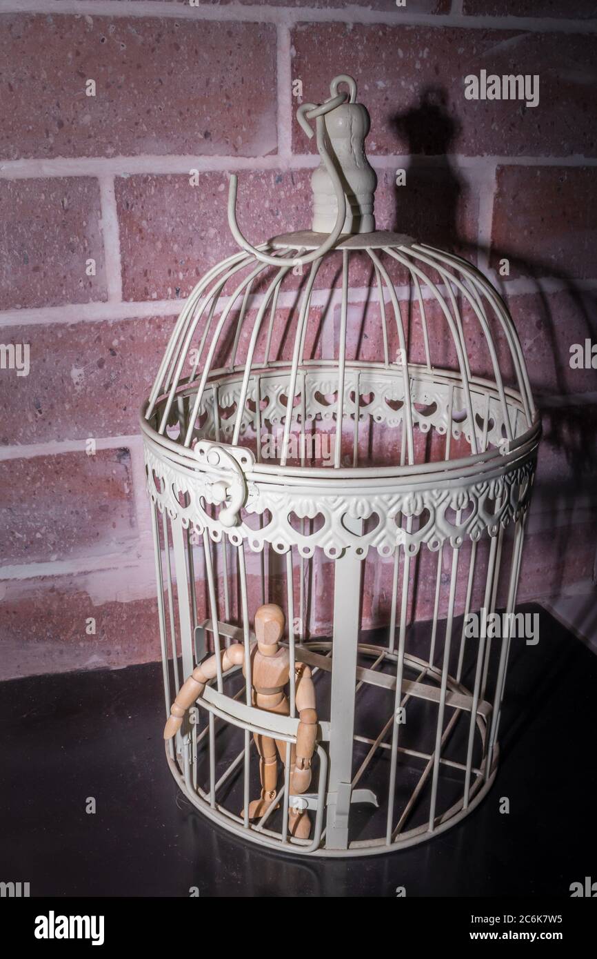 Wooden Human Manikin locked inside a white ornamental bird cage Stock Photo  - Alamy