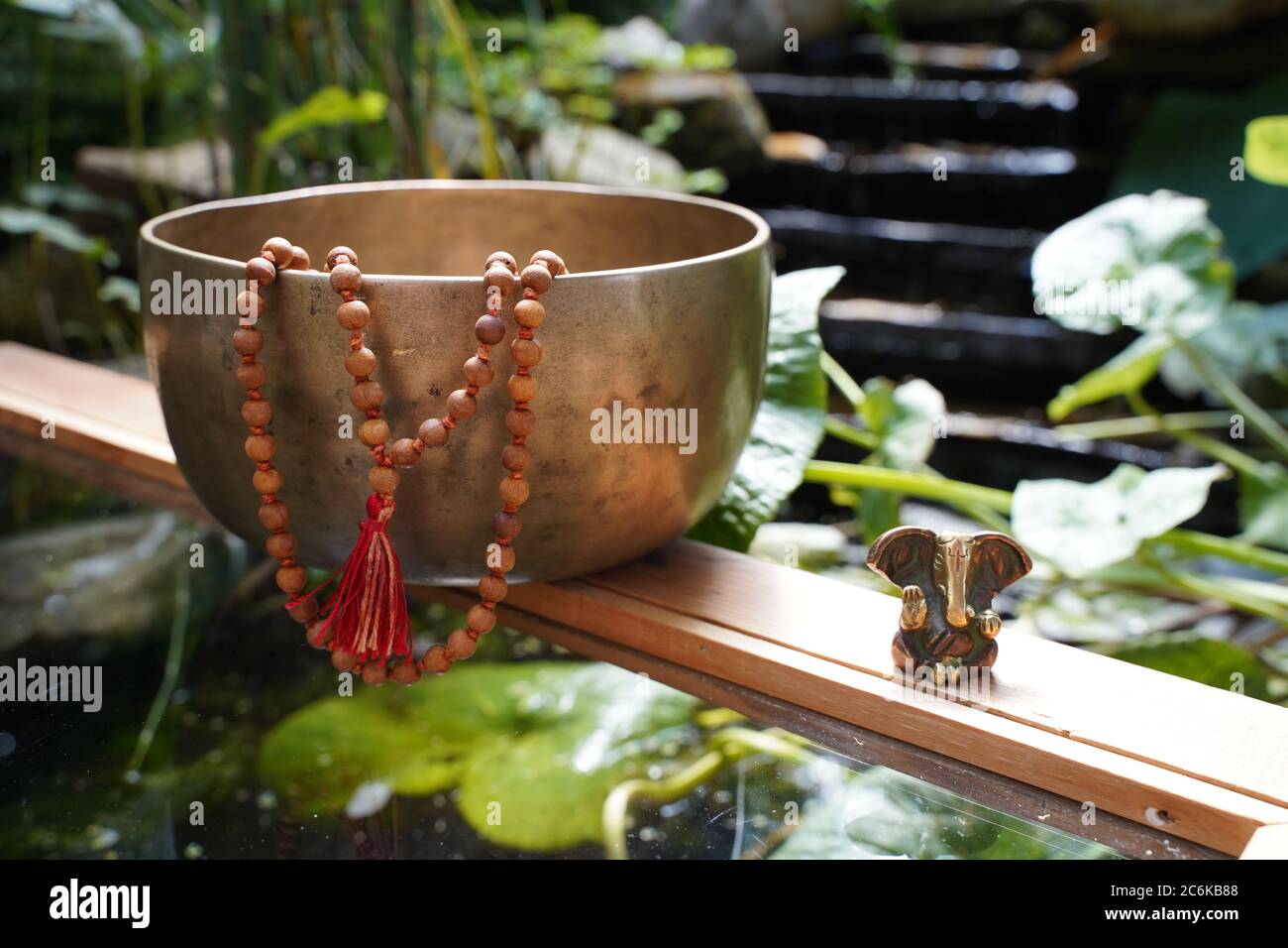 Tibetan singing bowl close up with beautiful woodon Mala and Ganesha Deity for sound healing Stock Photo