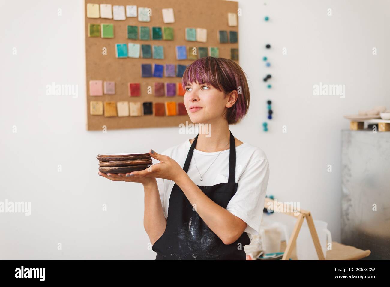 Pretty girl with colorful hair in black apron and white T-shirt holding ...