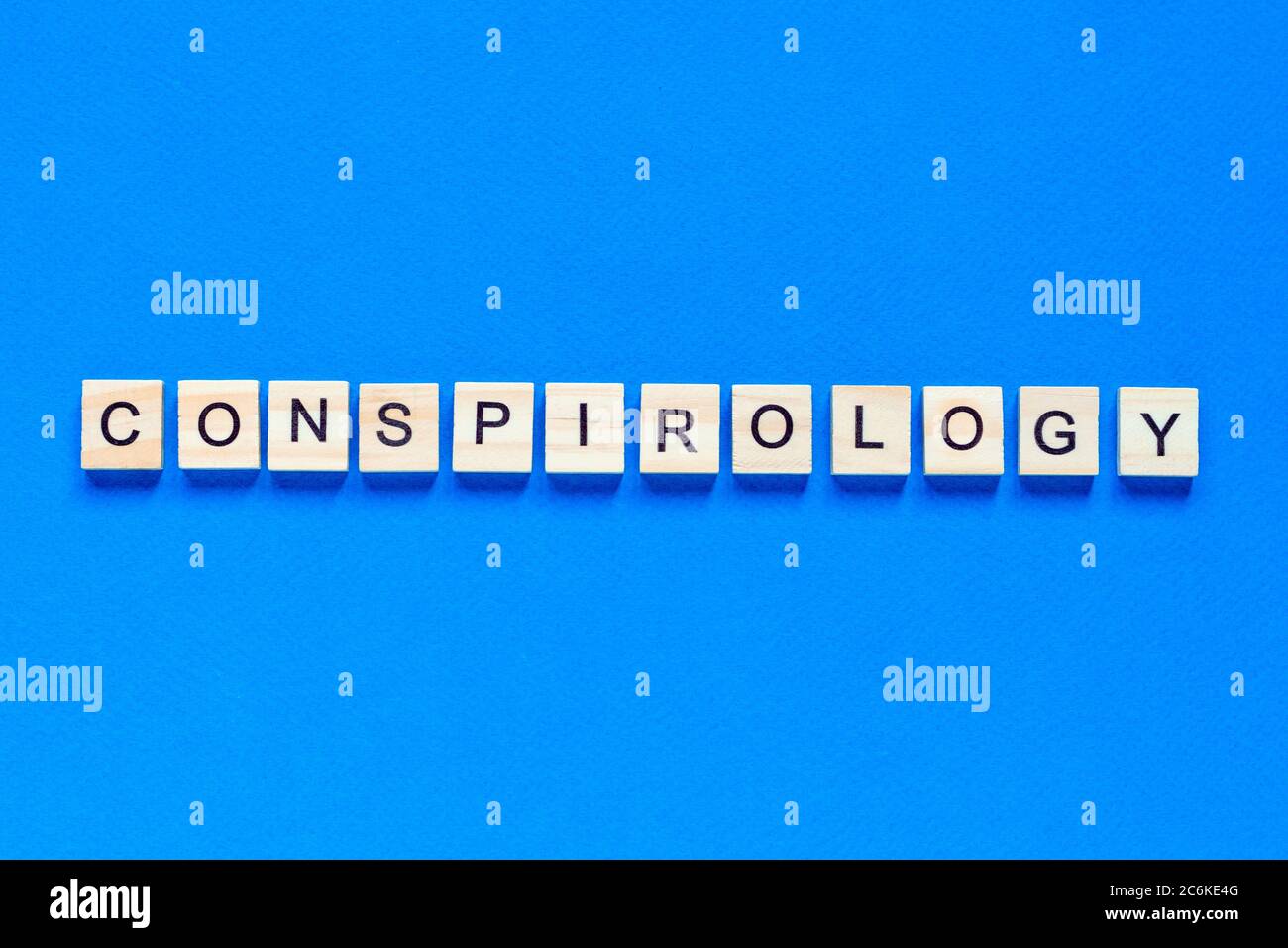 Conspirology - words made of wooden blocks with letters, secret plan of powerful people, conspiracy theory concept, top view blue background. Stock Photo