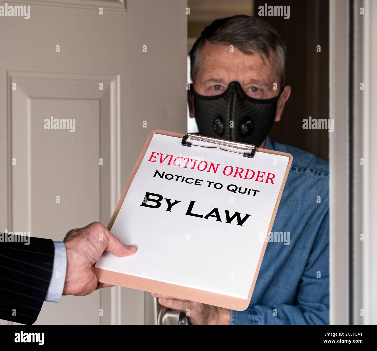 Open front door with man in suit handing an eviction notice to a defaulting renter with face mask during coronavirus epidemic Stock Photo
