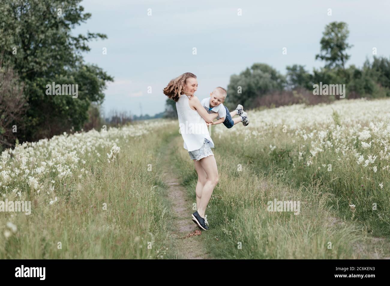Smiling mother playing with her little son in nature. Mom holding son in the arms and doing plane. Mother and son. Happy family Stock Photo