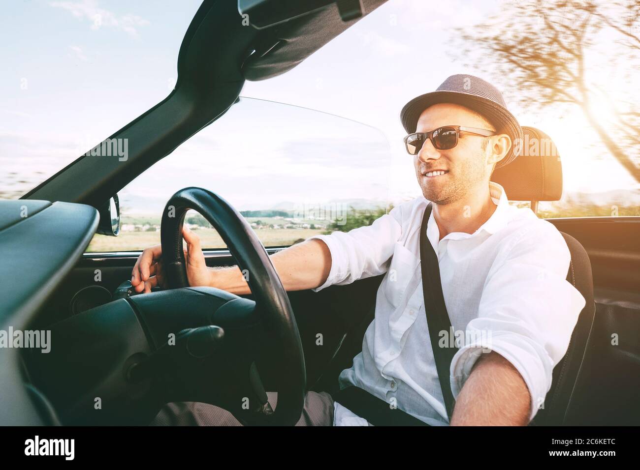 Smiling Man driving cabriolet car by province mountain road inside car view Stock Photo