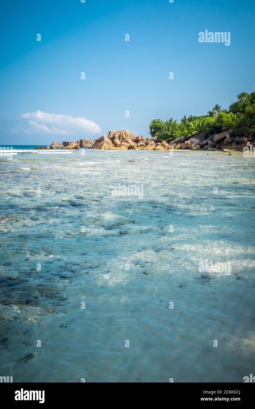 portrait format of nice tropical sandy beach with famous granite rocks on Anse Coco beach, La Digue Island, Seychelles. Holiday and vacation concept. Stock Photo