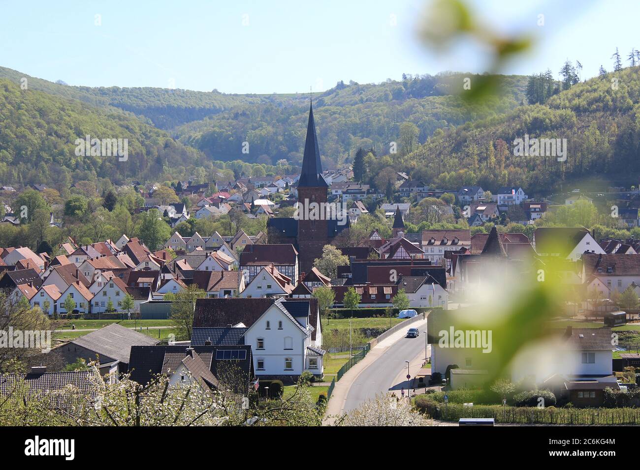 Small town view of Luegde,Germany in spring with church in center and blurry blossoms. Stock Photo