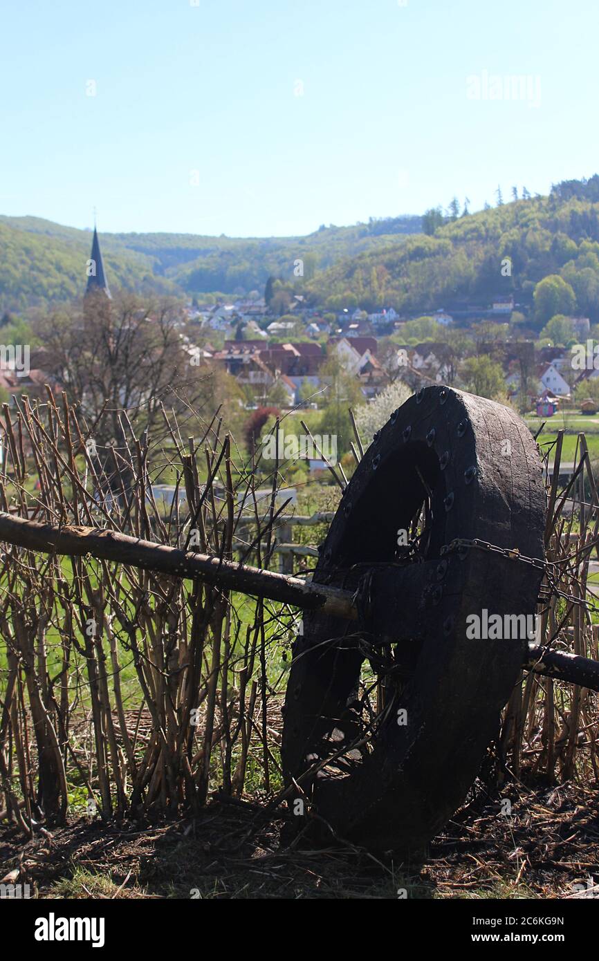 Wooden wheel used for Easter tradition with village of Luegde in the background. Stock Photo