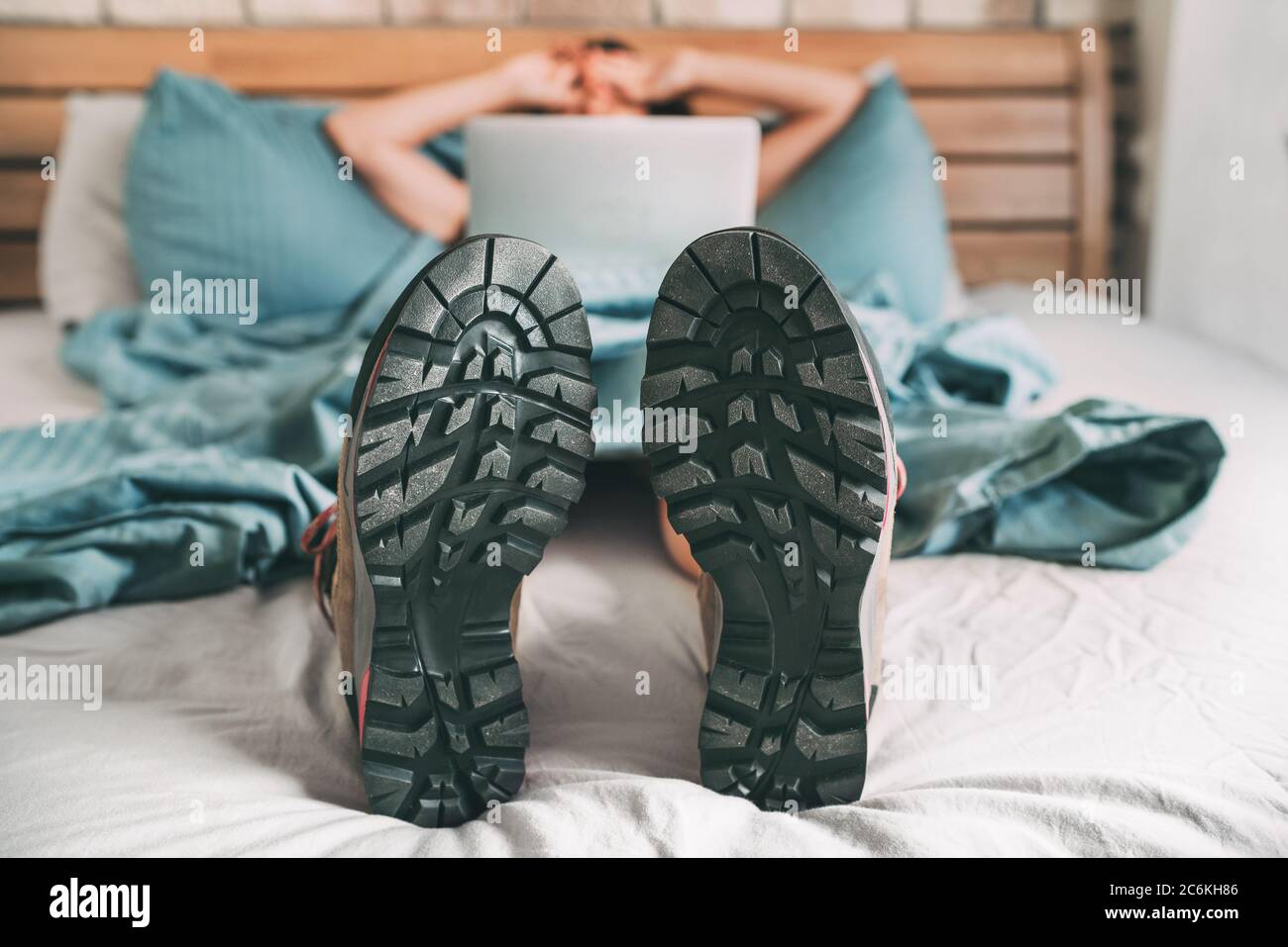 All time ready for trekking. Hiker was sleeping in comfort trekking boots and now she browsing an internet using a laptop and lazily stretching after Stock Photo