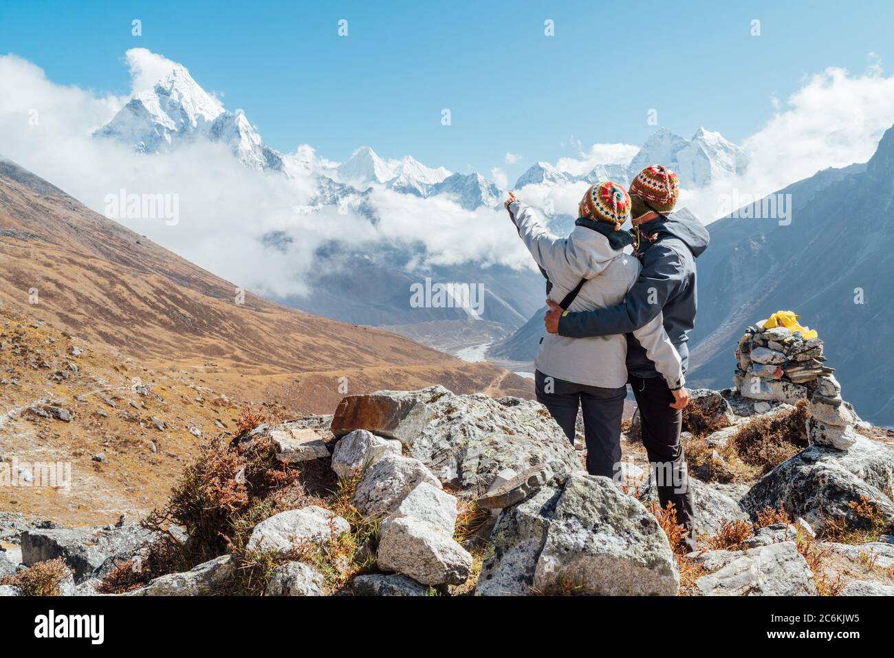 Couple having a rest on Everest Base Camp trekking route near Dughla 4620m. Backpackers left Backpacks, embracing and enjoying valley view with Ama Da Stock Photo