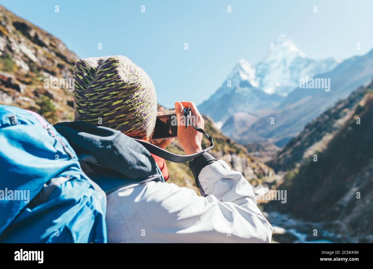 Young hiker backpacker female taking photo mountain view during high altitude Acclimatization walk. Everest Base Camp trekking route, Nepal. Active va Stock Photo