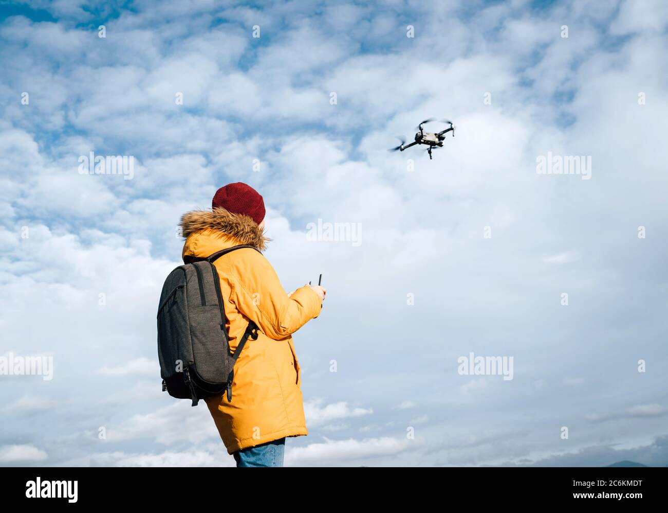 Teenager boy dressed yellow jacket piloting a modern digital drone using remote controller Stock Photo