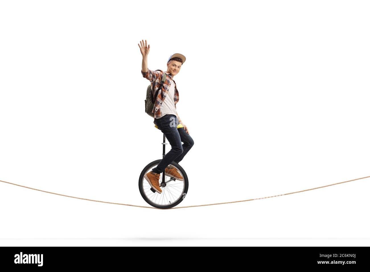 Young male student riding a unicycle on a rope and waving isolated on white background Stock