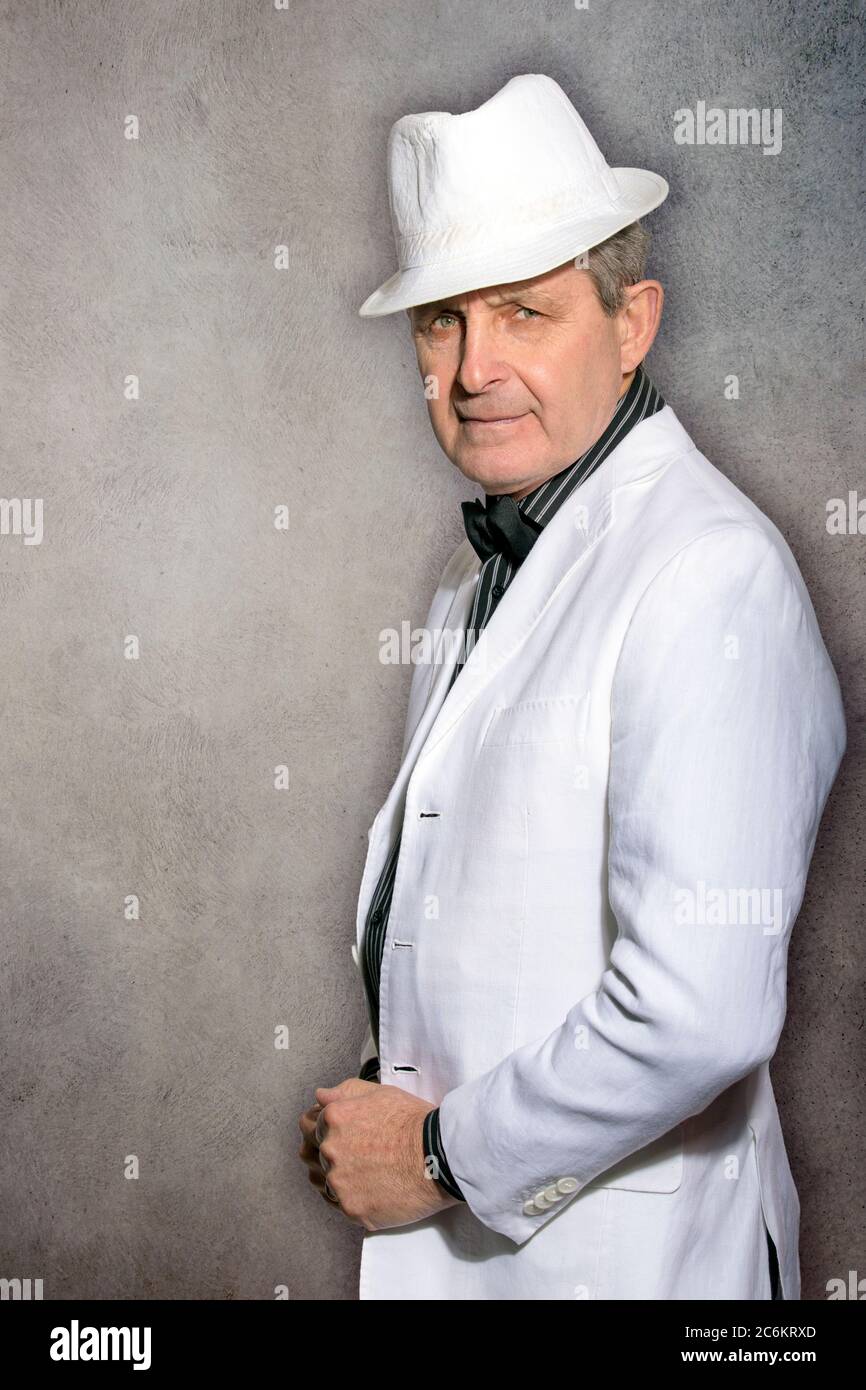 Attractive elderly man dressed in white with hat and elegant style Stock Photo