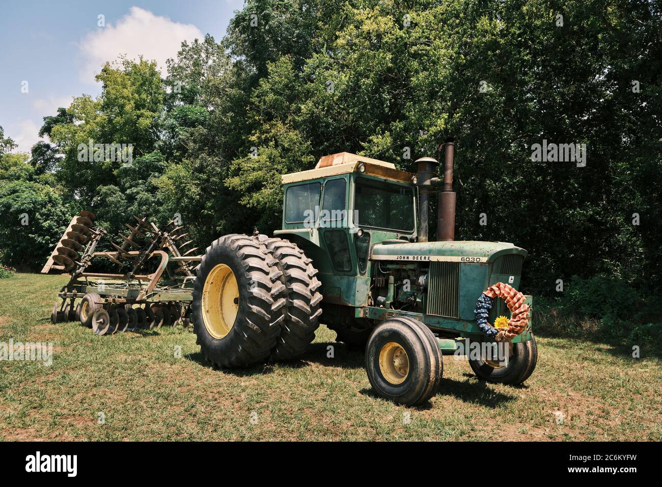John Deere 6030 tractor built in the 1970s pulling a tiller rig for tilling farm fields in Alabama, USA. Stock Photo