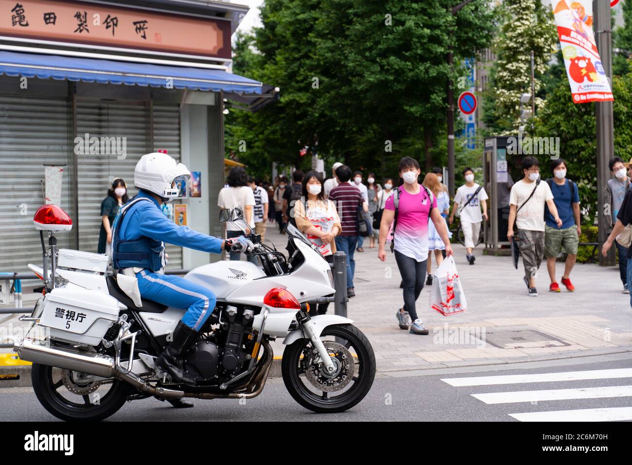 Akihabara, Japan- June 20, 2020: A policeman waits for people to cross the street  in Akihabara. Stock Photo
