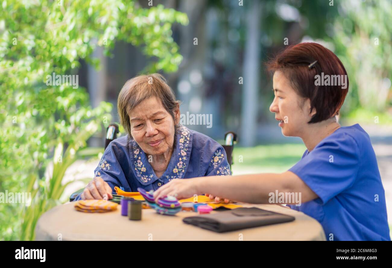 Elderly woman with caregiver in the needle crafts occupational therapy  for Alzheimer’s or dementia Stock Photo