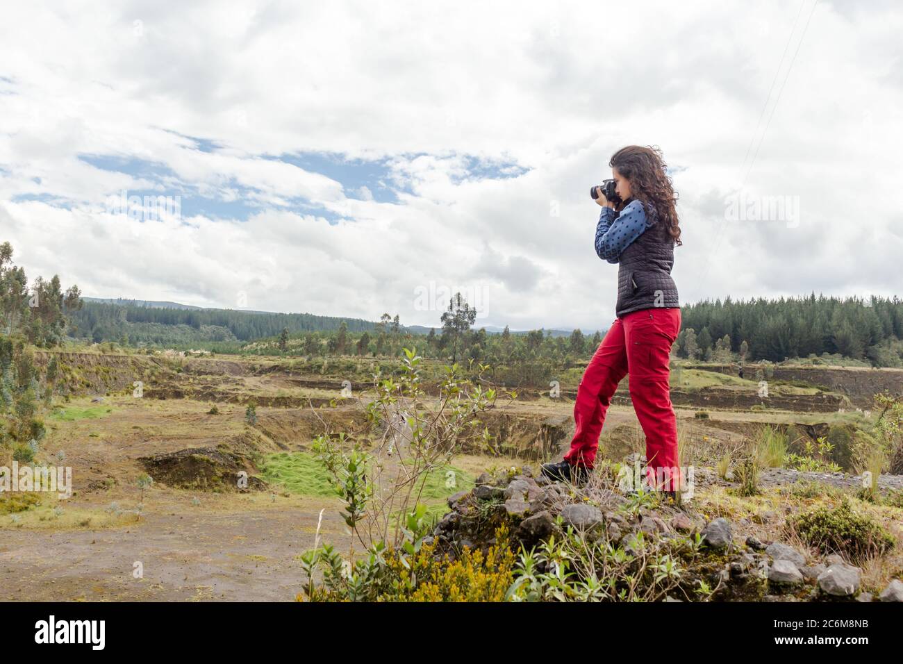 Close-up of a woman taking pictures of a landscape on a cliff Stock Photo