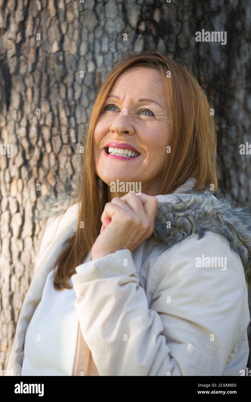 Portrait attractive mature woman in warm  winter jacket outdoor, posing happy relaxed, friendly and thoughtful, blurred background. Stock Photo