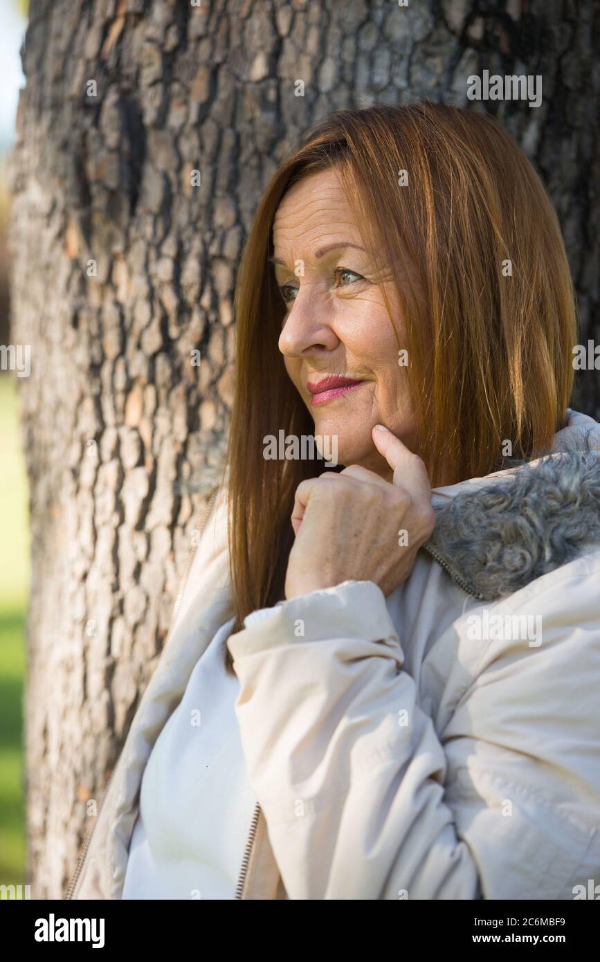 Portrait attractive mature woman in warm jacket outdoor, posing thoughtful relaxed, friendly and confident, blurred background. Stock Photo