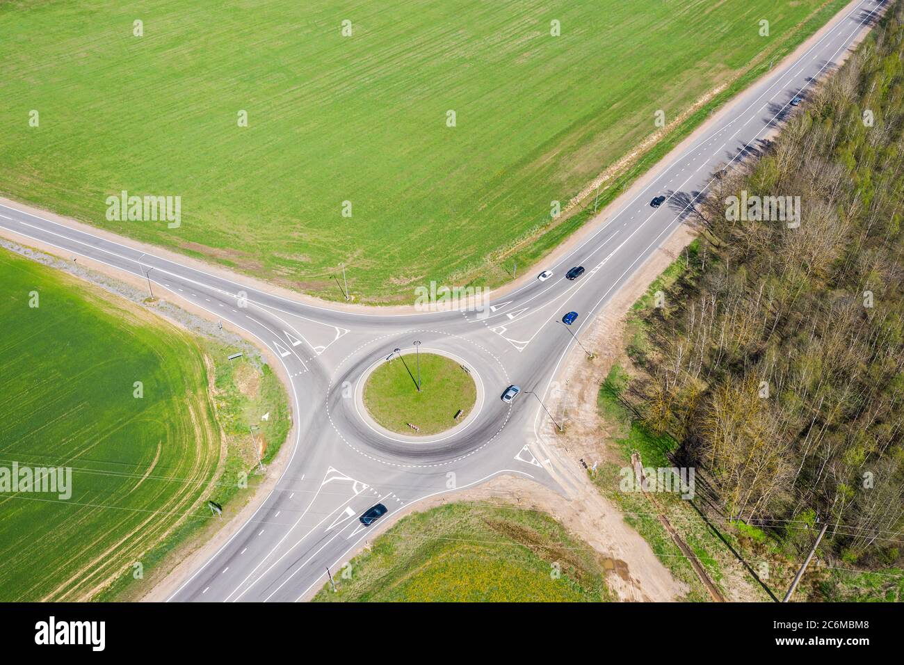 roads with roundabout junction, traffic of cars and agriculture fields ...