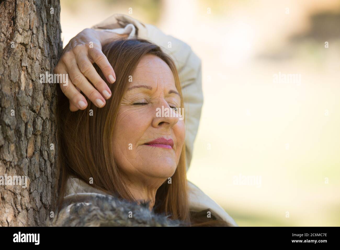 Portrait attractive mature woman relaxed in park with closed eyes, daydreaming, contemplating, thoughtful, blurred background and copy space. Stock Photo