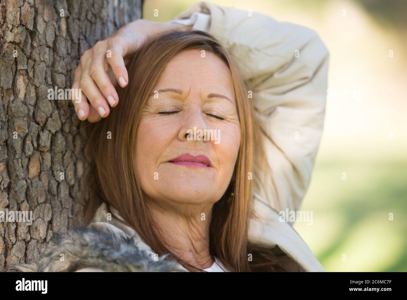 Portrait attractive mature woman relaxed in park with closed eyes, daydreaming, contemplating, thoughtful, blurred background. Stock Photo