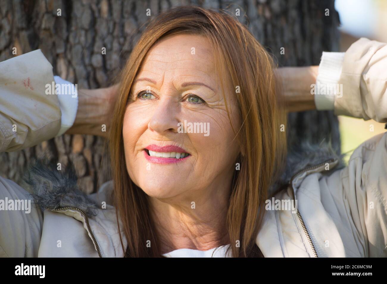 Portrait attractive mature woman with long hair posing happy relaxed, thoughtful and confident outdoors in park, friendly positive smile. Stock Photo
