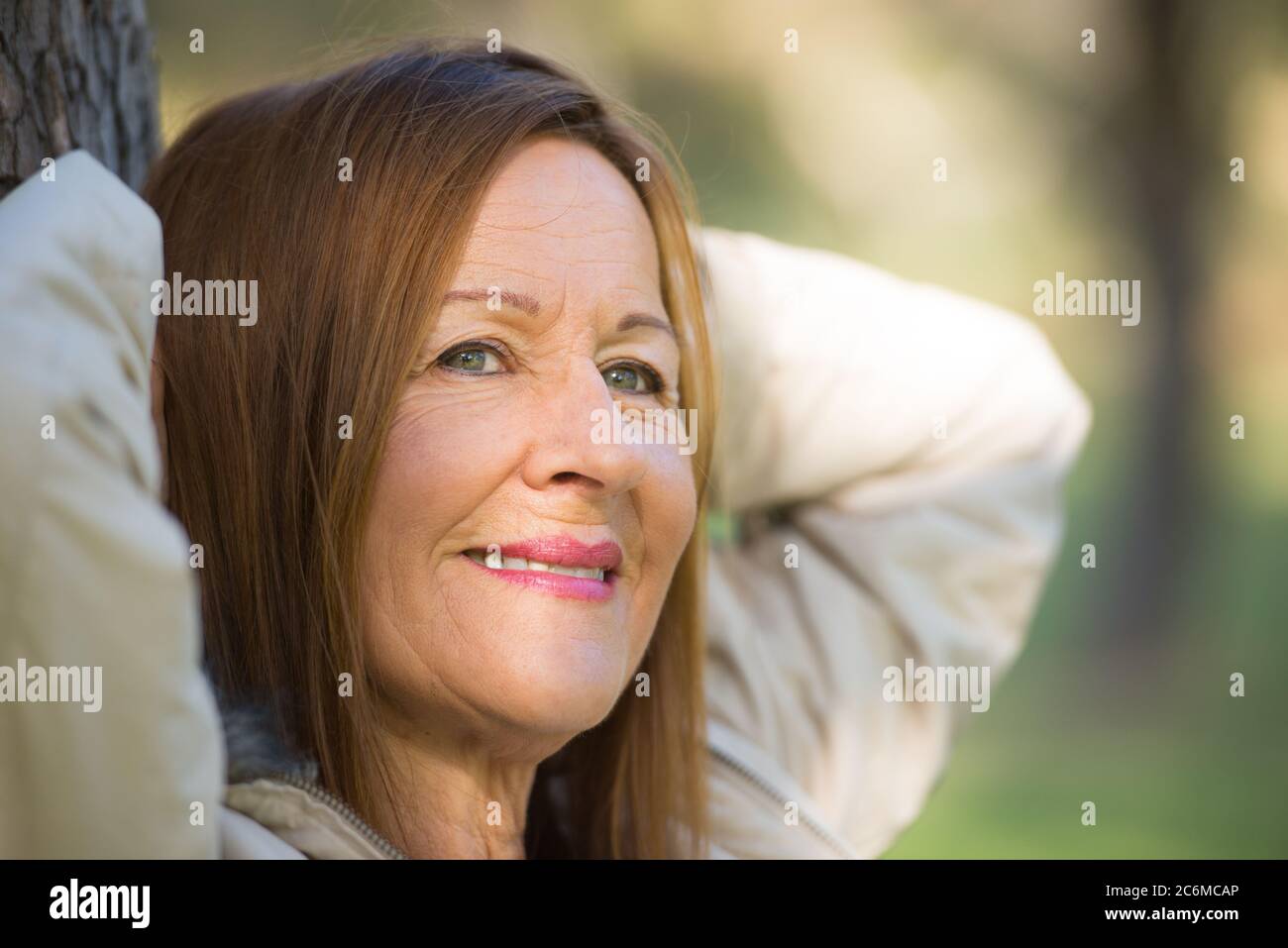 Portrait attractive mature woman with long hair posing happy relaxed, thoughtful and confident outdoors in park, joyful smile. Stock Photo