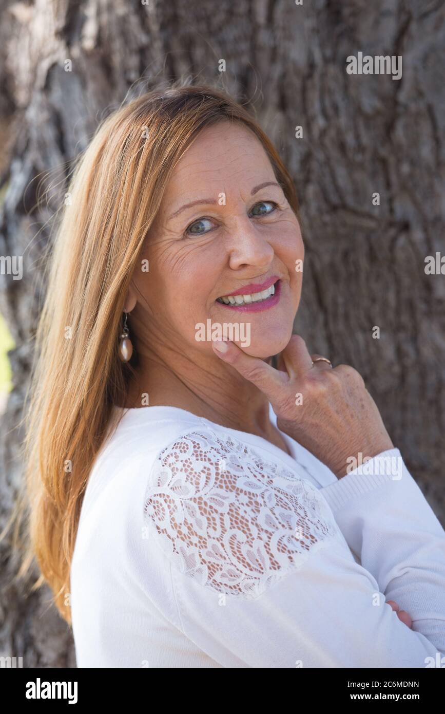 Portrait attractive mature woman posing thoughtful outdoors, contemplating, happy friendly relaxed smile. Stock Photo