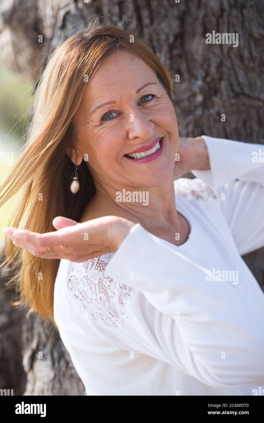 Portrait attractive mature woman posing thoughtful outdoors, contemplating, happy friendly relaxed smile. Stock Photo